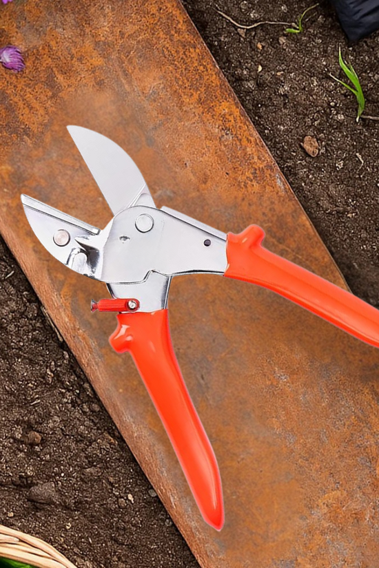 Gardening shears with orange handles on a rusty metal surface near soil and plants.