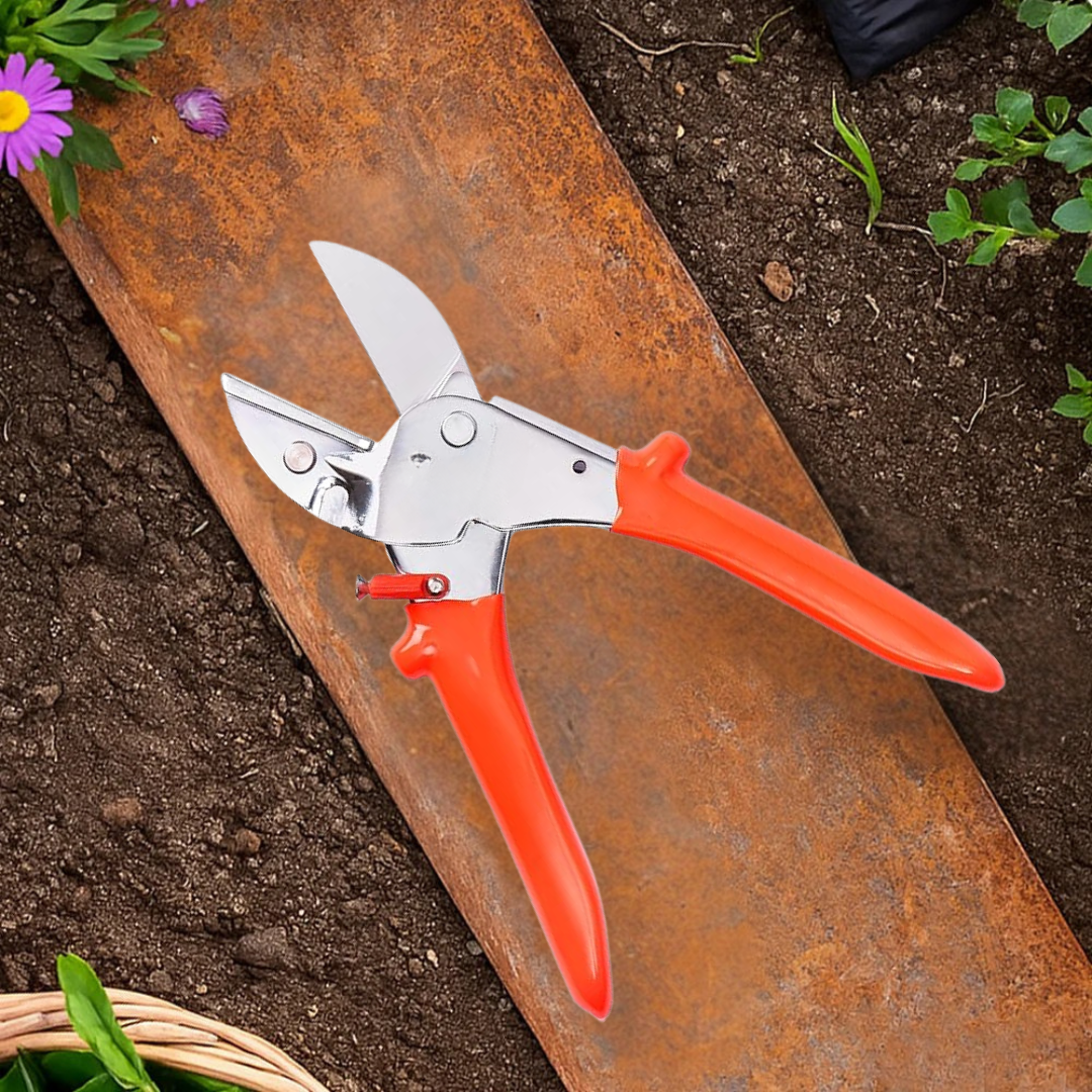 Gardening shears with orange handles on a rusty metal surface near soil and plants.